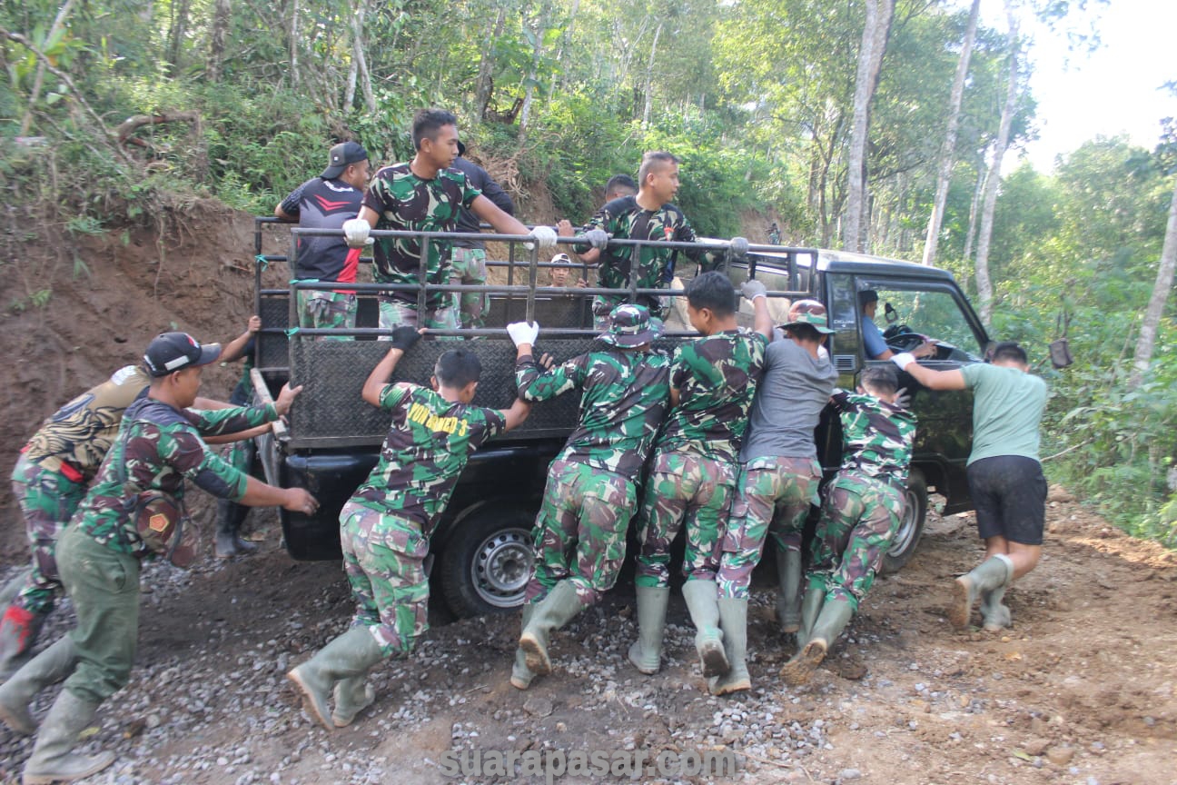 Puluhan Anggota Satgas TMMD Bersama-sama Mendorong Mobil Pengangkut Material Kricak yang Terjebak Tanah Becek